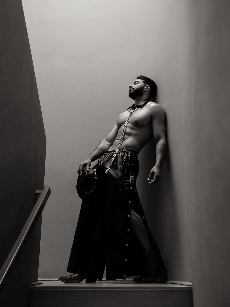 Menswear editorial: a long skirted look on a staircase, head tipped back, black and white