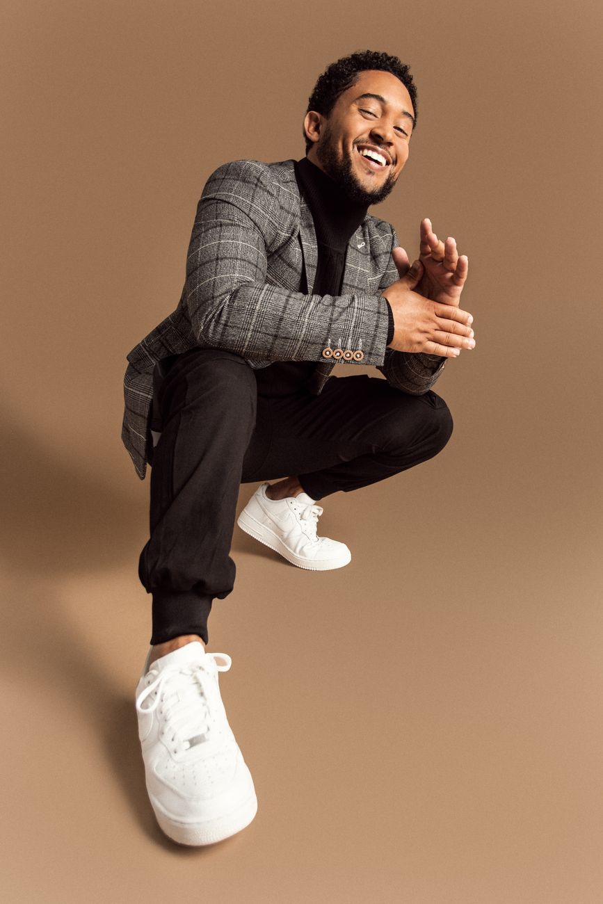 Actor Tahj Mowry in a grey checked blazer, black trousers and white sneakers, styled by Quentin Fears